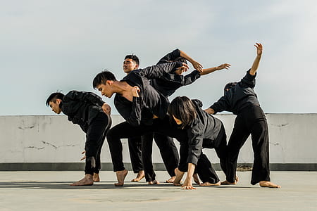 Six People in Black Matching Clothes Dancing at Daytime thumbnail