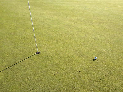 golf ball on gold field near hole thumbnail