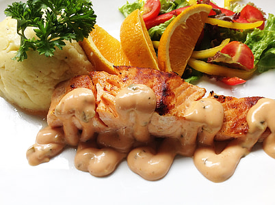grilled fish covered in sauce with slices of orange, and mash potat thumbnail