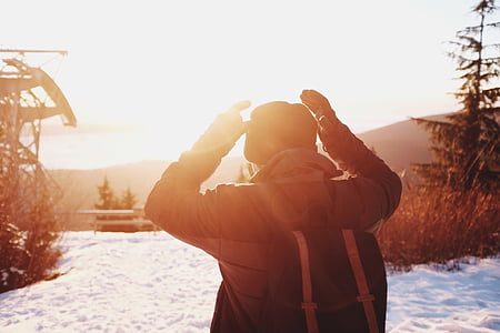 man wearing black jacket and holding blue and orange backpack thumbnail