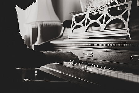 grayscale photo of person playing upright piano thumbnail