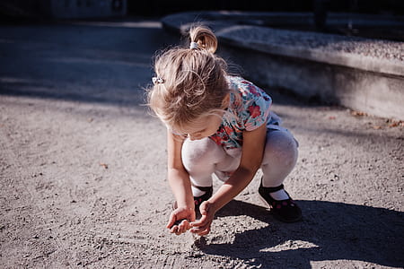 girl wearing multicolored floral shirt holding grey sand thumbnail