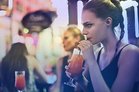 Woman Wearing Black Spaghetti Strap Top and Sipping Drink thumbnail
