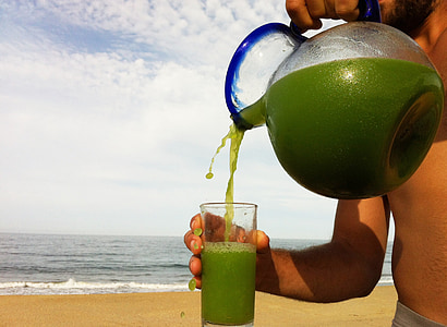 person pouring pitcher in glass beside body of water thumbnail
