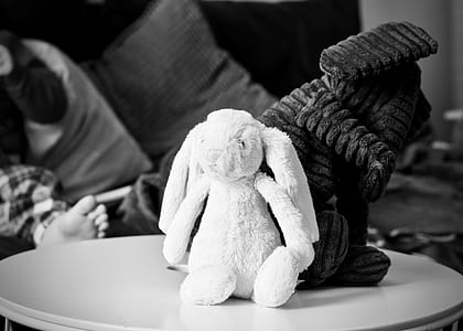 grayscale photography of rabbit plush toy on wooden top table thumbnail