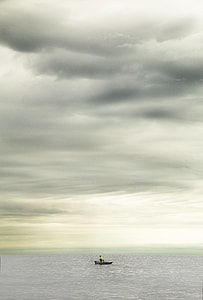 black boat on body of water under white clouds at daytime thumbnail
