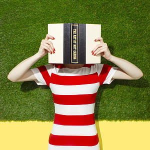 woman in white and red striped crew-neck shirt holding The Art of Not Caring book thumbnail