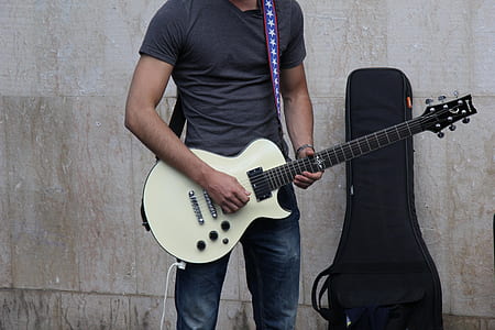 man playing guitar near gray concrete wall thumbnail