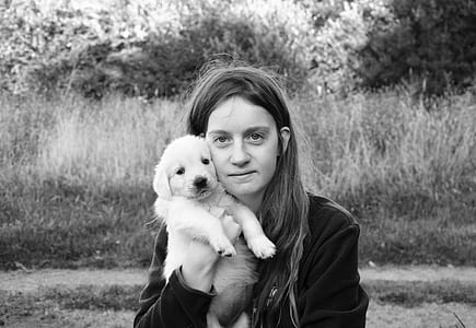 gray scale photography of woman carrying puppy thumbnail