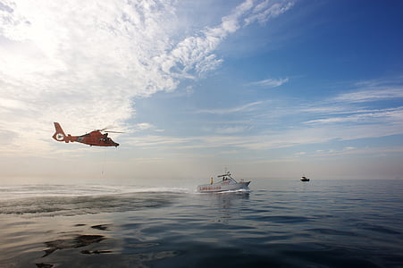 red helicopter above body of water with boat thumbnail