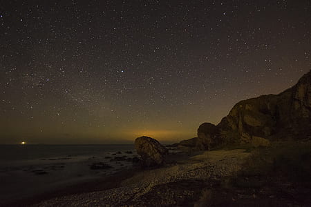time-lapse photography of brown rock formation under stars thumbnail