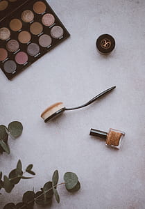 black handled makeup brush near brown polish bottle and makeup palette thumbnail