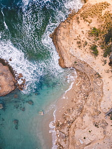 body of water near brown cliff thumbnail