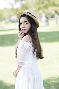 girl wearing straw hat and black bohemian dress standing on green grass during daytime thumbnail