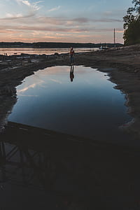 woman standing beside body of water thumbnail