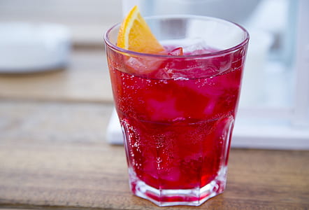 close-up photography of clear drinking glass with pink-colored beverage with ice and sliced on lemon thumbnail