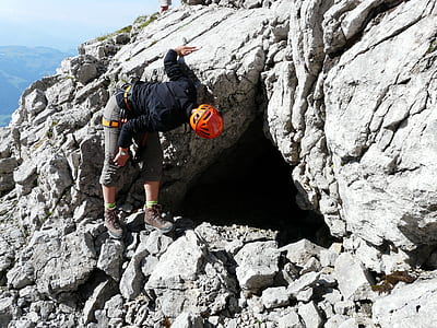 person wearing orange bicycle helmet peeping inside cave thumbnail