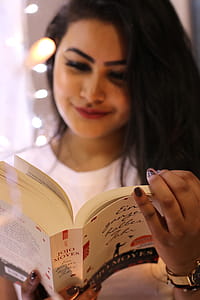 Woman Wearing White Crew-neck Shirt Holding Jojo Moyes Book thumbnail