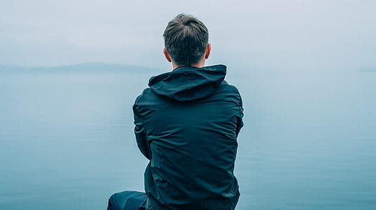 man sitting near body of water thumbnail