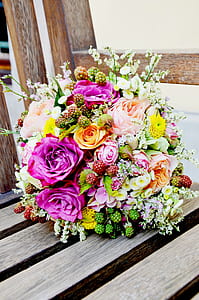 close-up photo of rose flowers, raspberries, bellis flowers, and chrysantheum flowers bouquet on brown wooden surface thumbnail