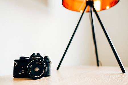 black Nikon DSLR camera on table near table lamp thumbnail