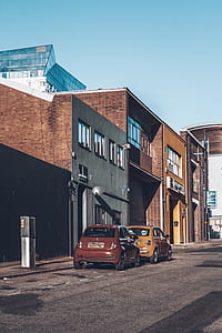 two red and yellow 3-door hatchbacks parked on roadside at daytime thumbnail