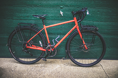orange and black road bike near green wooden panel thumbnail
