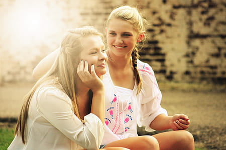 woman in white scoop neck shirt touching the woman's hair while sitting thumbnail