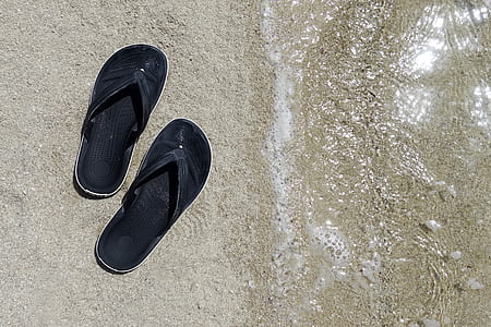 pair of black flip-flops on seashore thumbnail