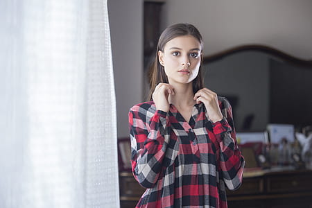 woman wearing white, red, and black sport shirt standing near white curtain thumbnail