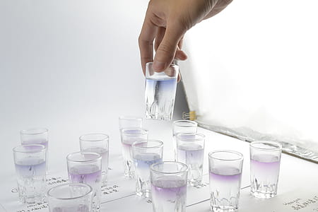 person holding drinking glass filled with liquid thumbnail