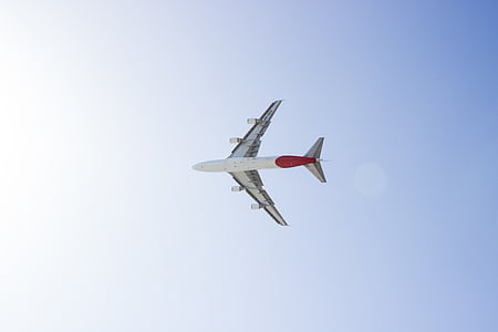 low-angle photography of white and red plane on mid-air under blue and white sky during daytime thumbnail