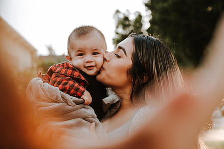 woman carrying baby while kissing left cheek thumbnail
