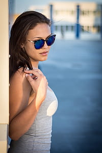 woman in blue sunglasses wearing grey top against the wall during daytime thumbnail