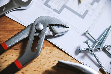 Pliers and nails on a wooden floor with house plans thumbnail