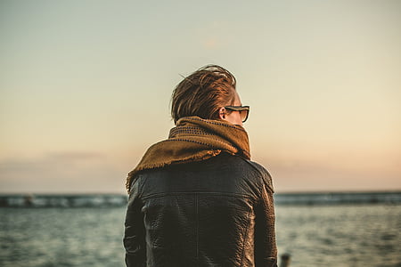 man with black leather jacket and brown scarf close-up photography thumbnail