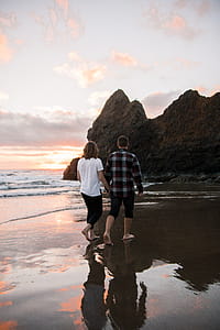 Couple Holding Each Others Hand While Walking on Shore thumbnail