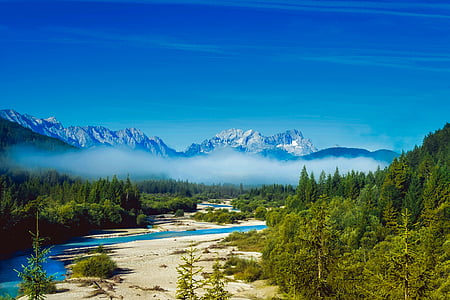 green trees near body of water and mountain during daytime thumbnail