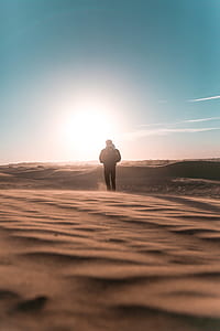 man walking towards in the middle of desert thumbnail