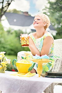 woman holding clear glass jar sitting on white chair thumbnail