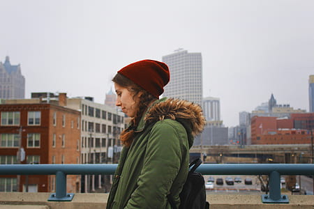 woman wearing green parka coat walking near wall with blue rails thumbnail