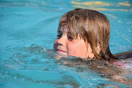 girl swims on body of water during daytime thumbnail