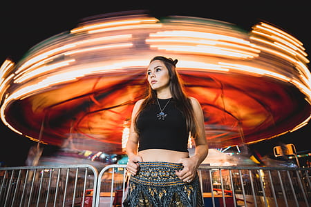 woman standing on gray fence beside carousel thumbnail