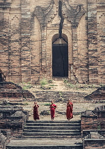 three kids wearing red traditional dress standing near brown building at daytime thumbnail