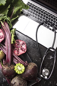 Macbook Pro With Stethoscope With Kiwi and Vegetables on Black Wooden Surface thumbnail