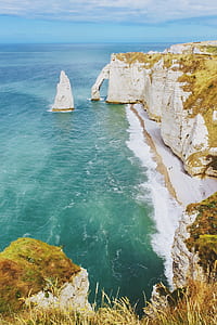 photo of beige mountains beside body of water during daytime thumbnail