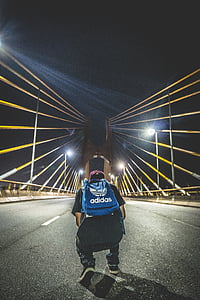 man with blue adidas backpack on the middle of the bridge thumbnail