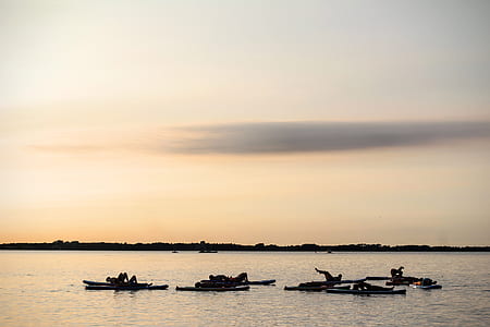 silhouette photo of persons on bamboo sticks on body of water thumbnail