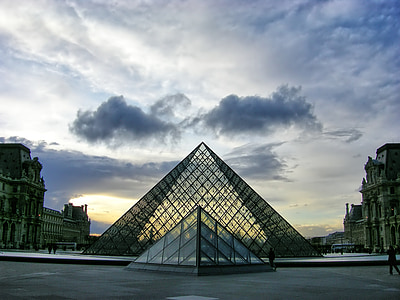 people walking toward gray pyramid metal building thumbnail