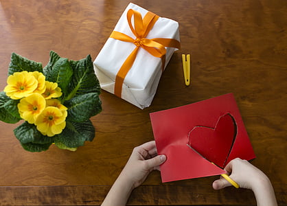 person cutting red construction paper near gift box thumbnail